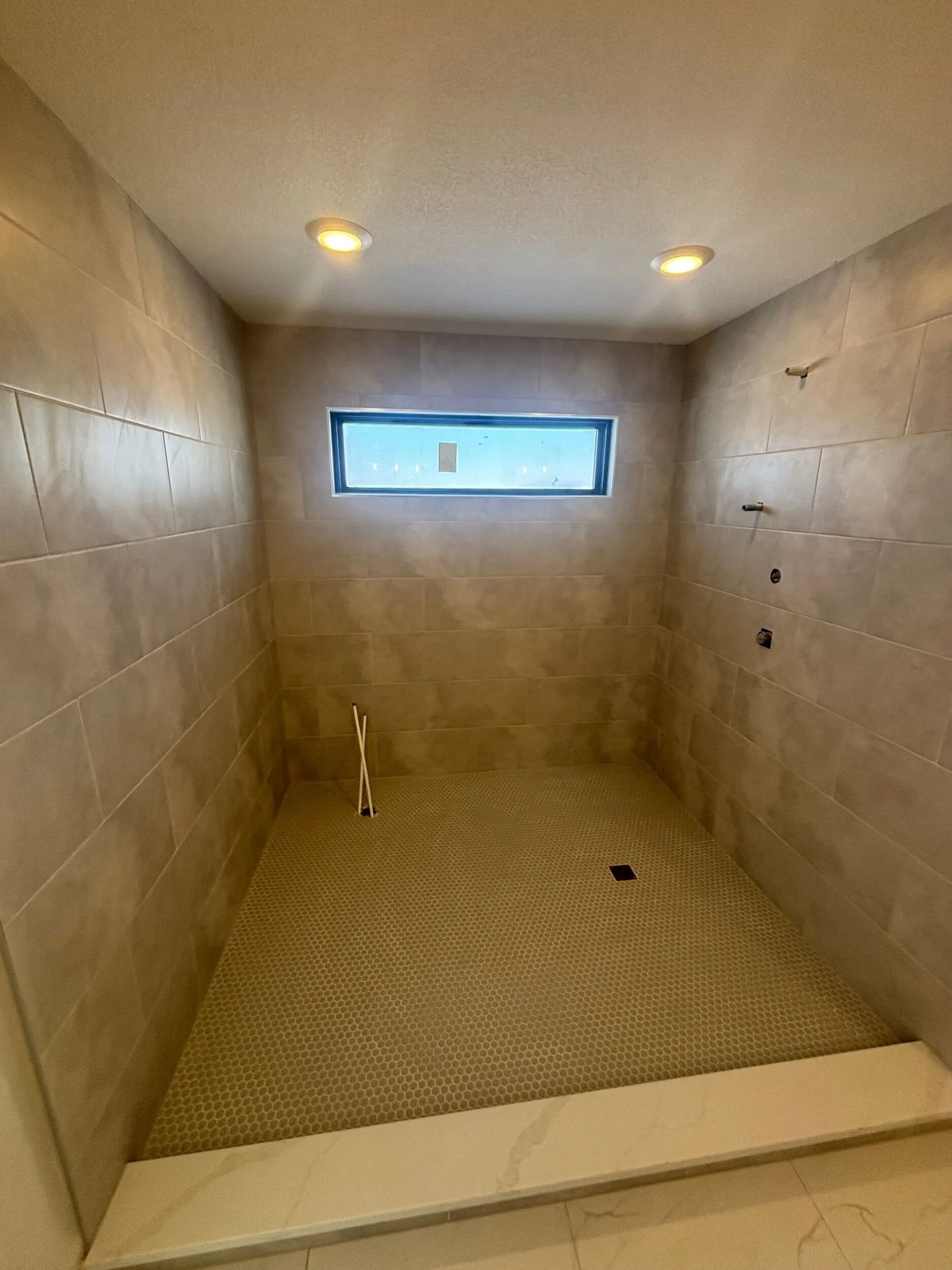 Tiled walk-in shower with linear drain, niche, and rain head