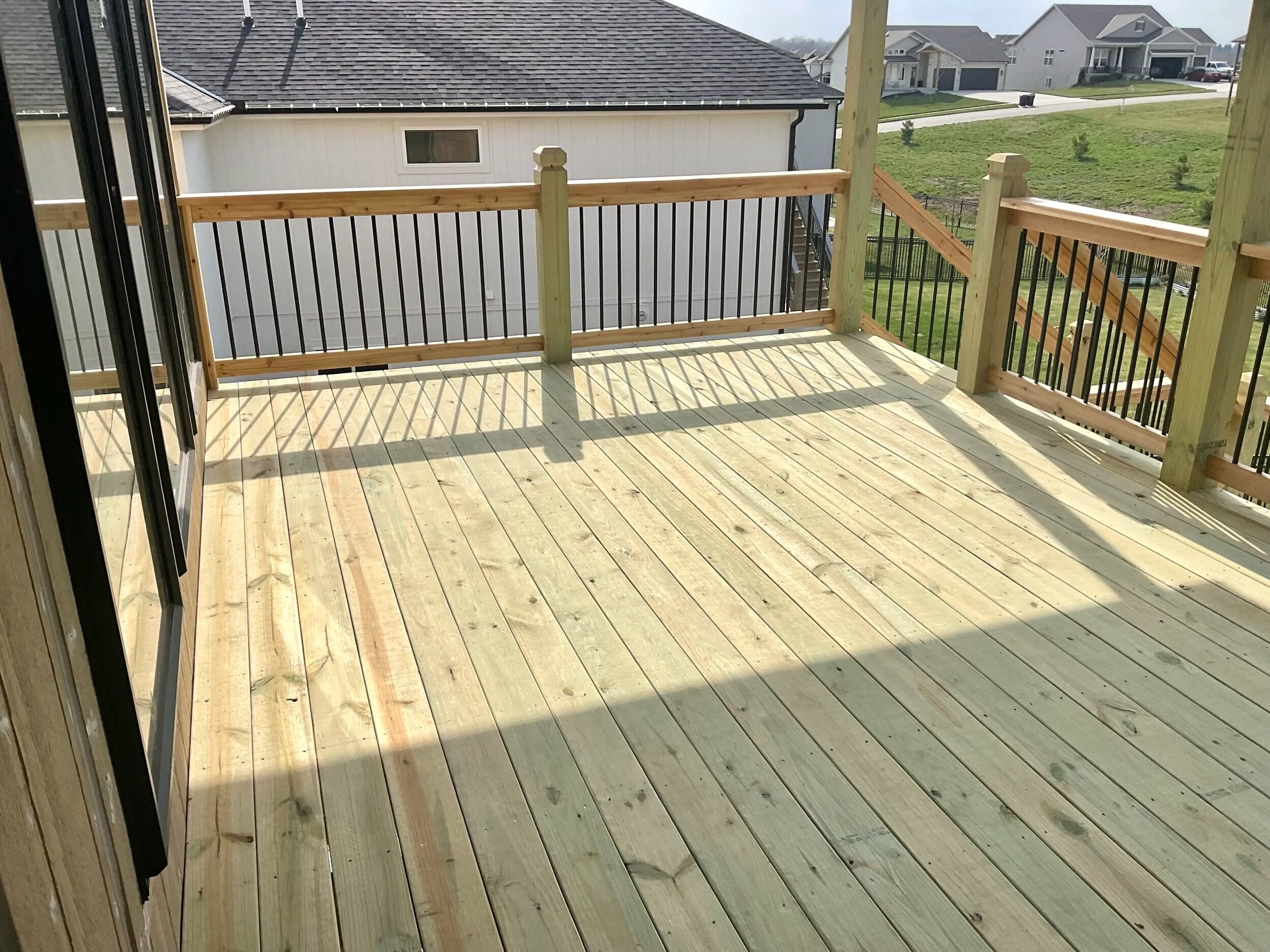 Wood deck with metal-baluster railing under a clear sky